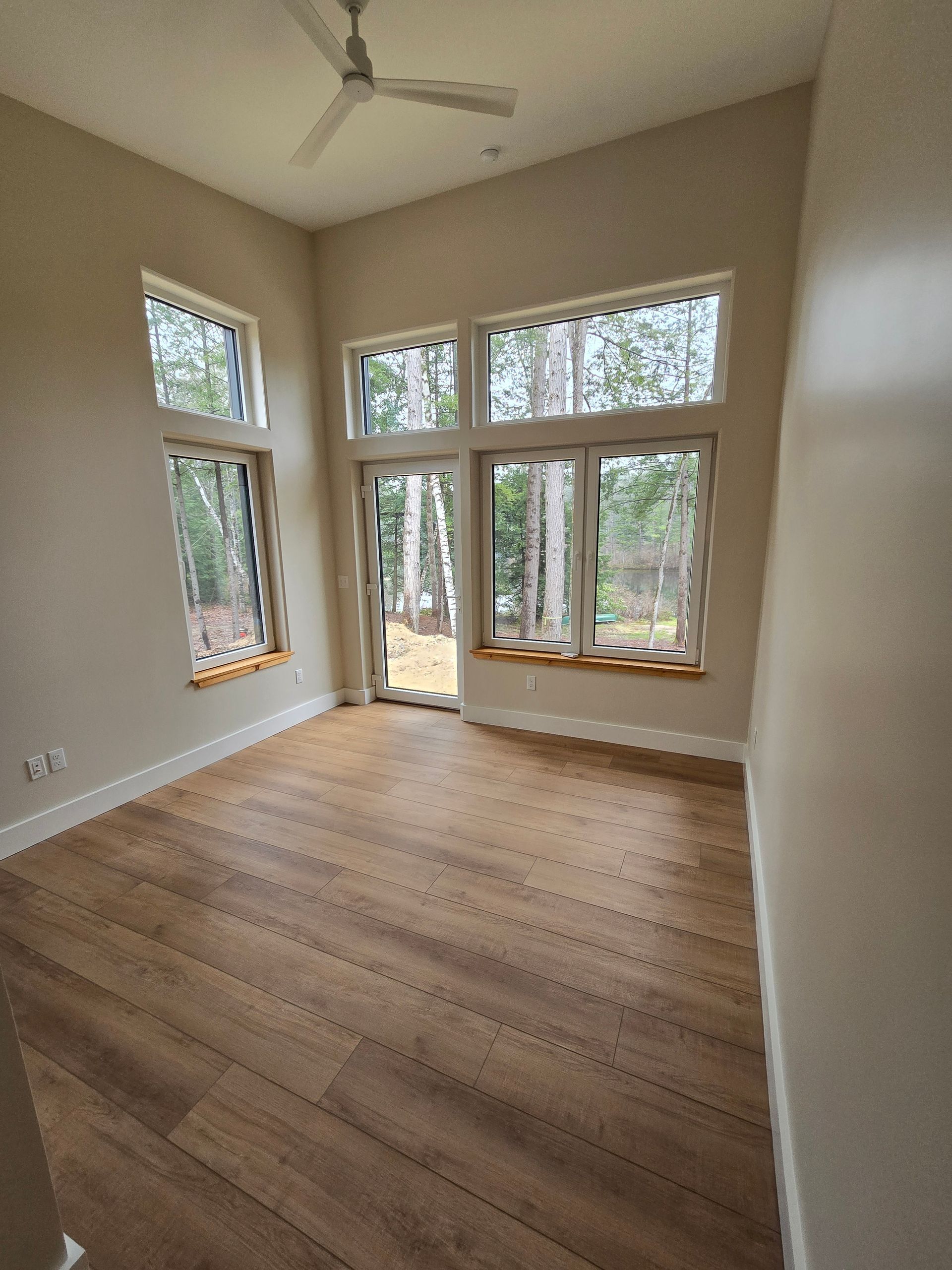 An empty room with hardwood floors and a ceiling fan.