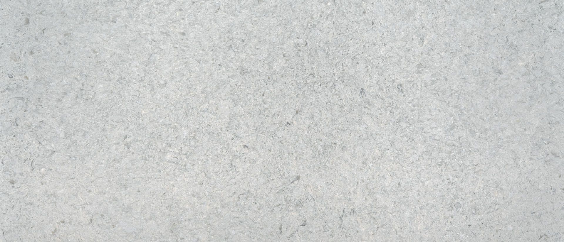 White, textured surface with small, dark specks, possibly a stone or concrete material.