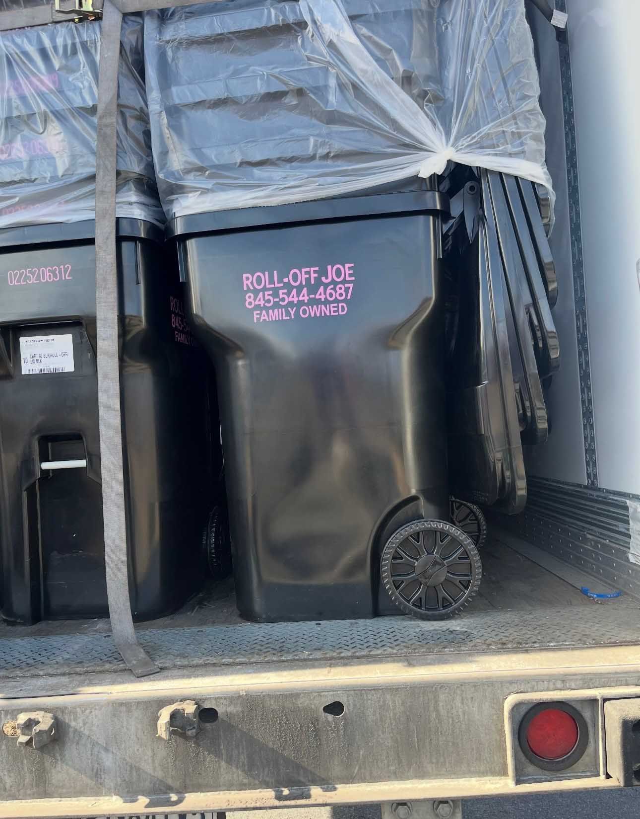 Black trash bins on a truck, labeled 