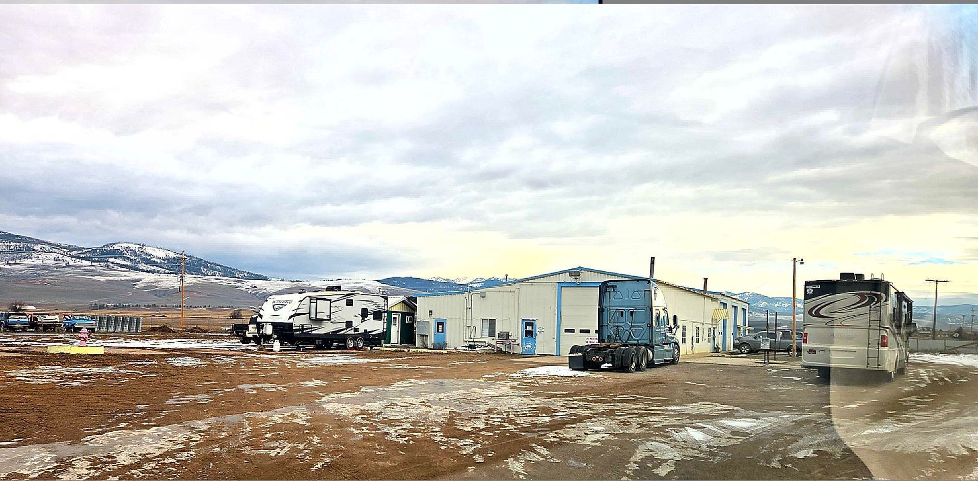 A truck parked in front of a building with a cloudy sky backdrop.