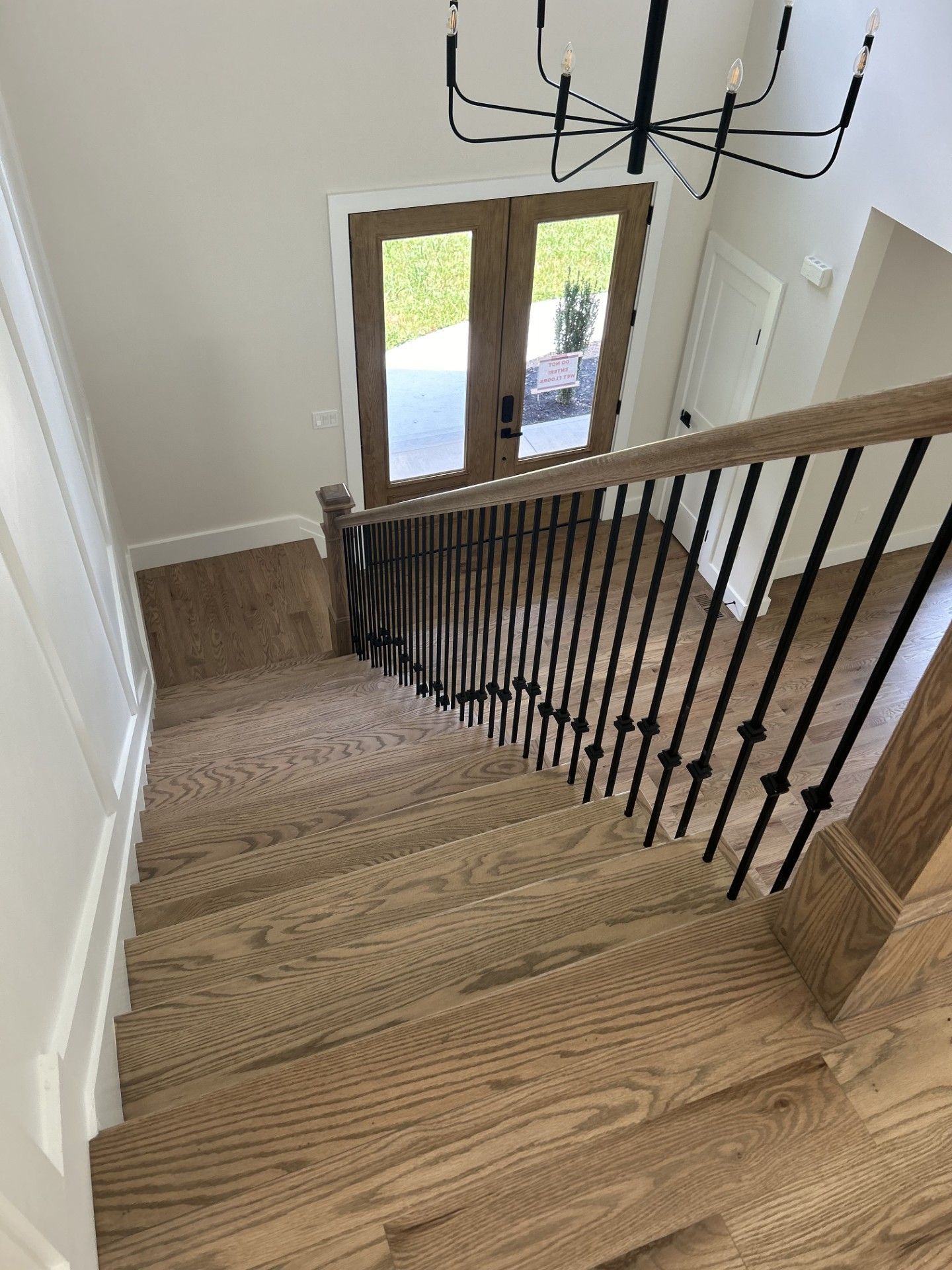 A wooden staircase with a black railing leading up to the second floor of a house.