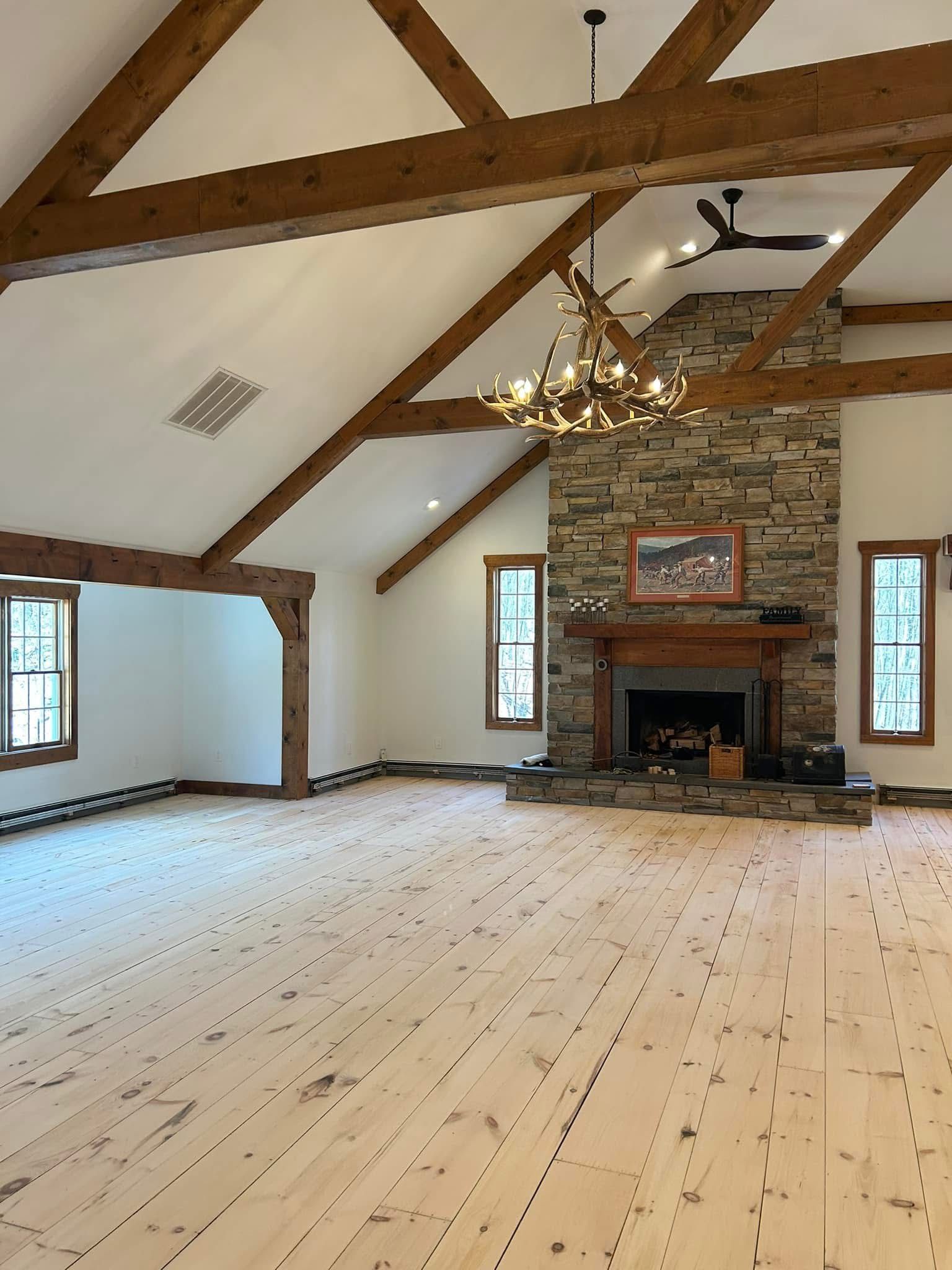 An empty room with wooden floors and a stone fireplace