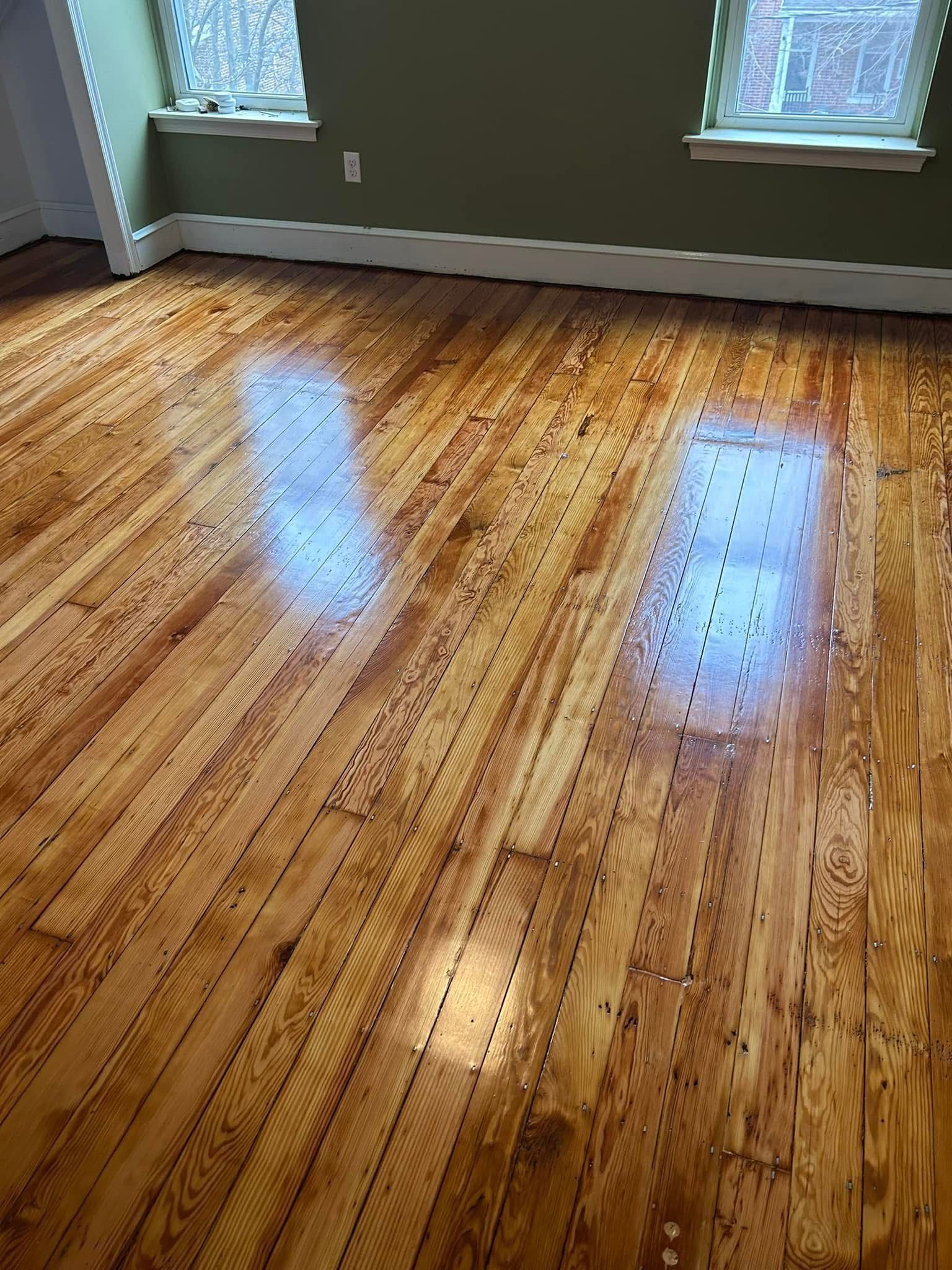 A room with a wooden floor and two windows.