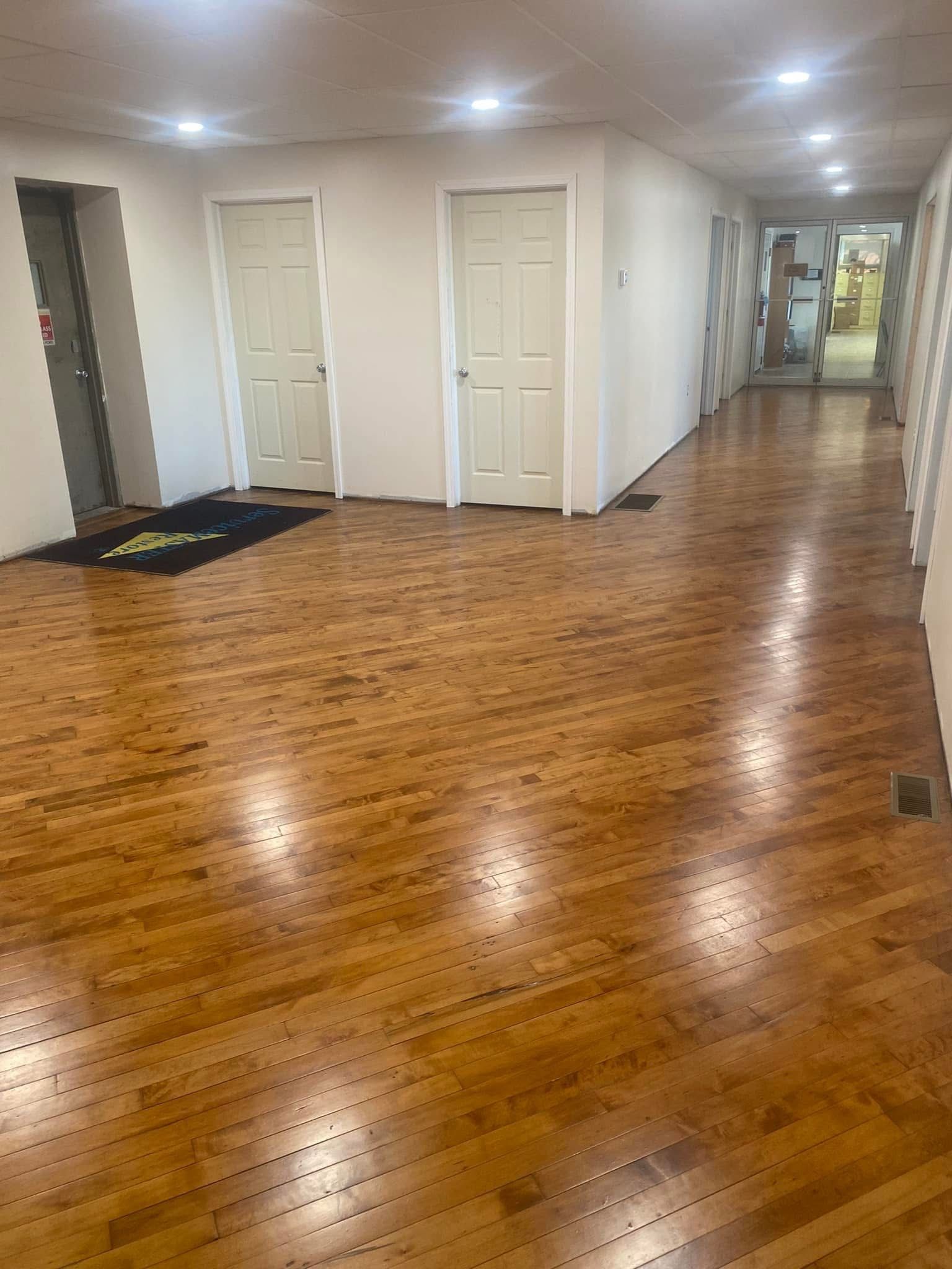 A long hallway with hardwood floors and white doors in a house.