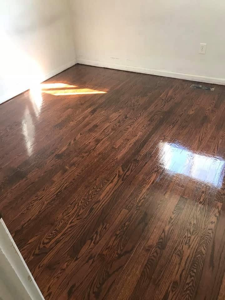 A bedroom with hardwood floors and white walls.