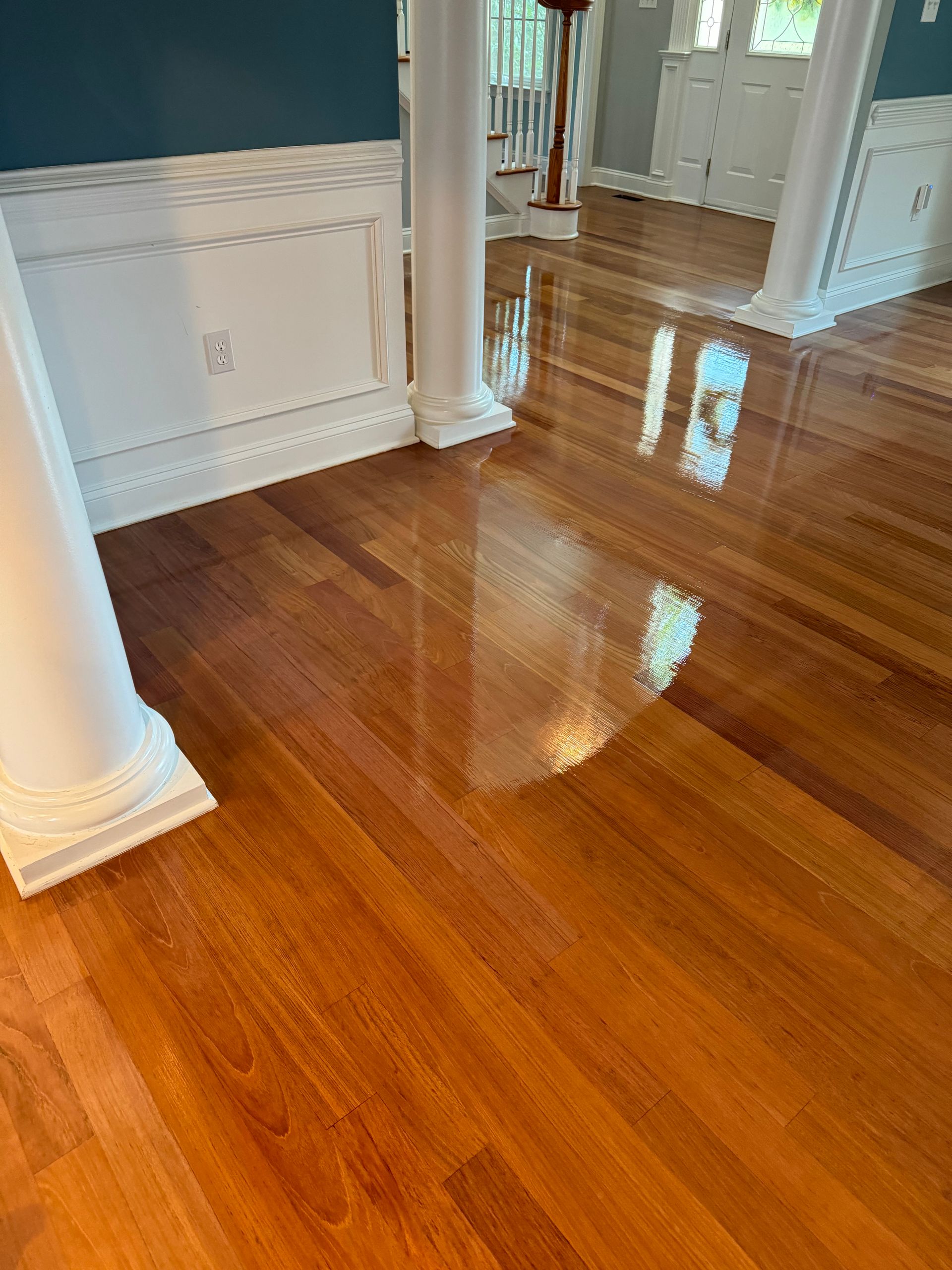 A living room with hardwood floors , columns , and a staircase.