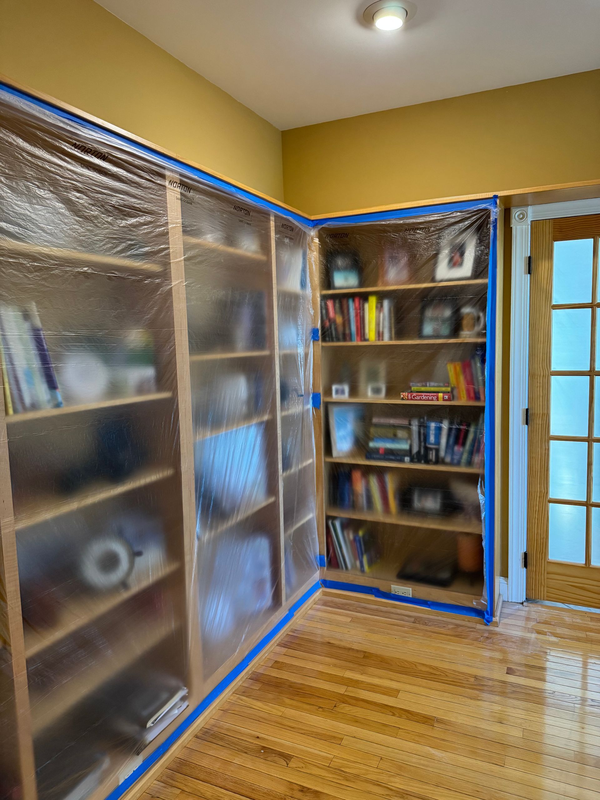 A room with shelves covered in plastic and a door.