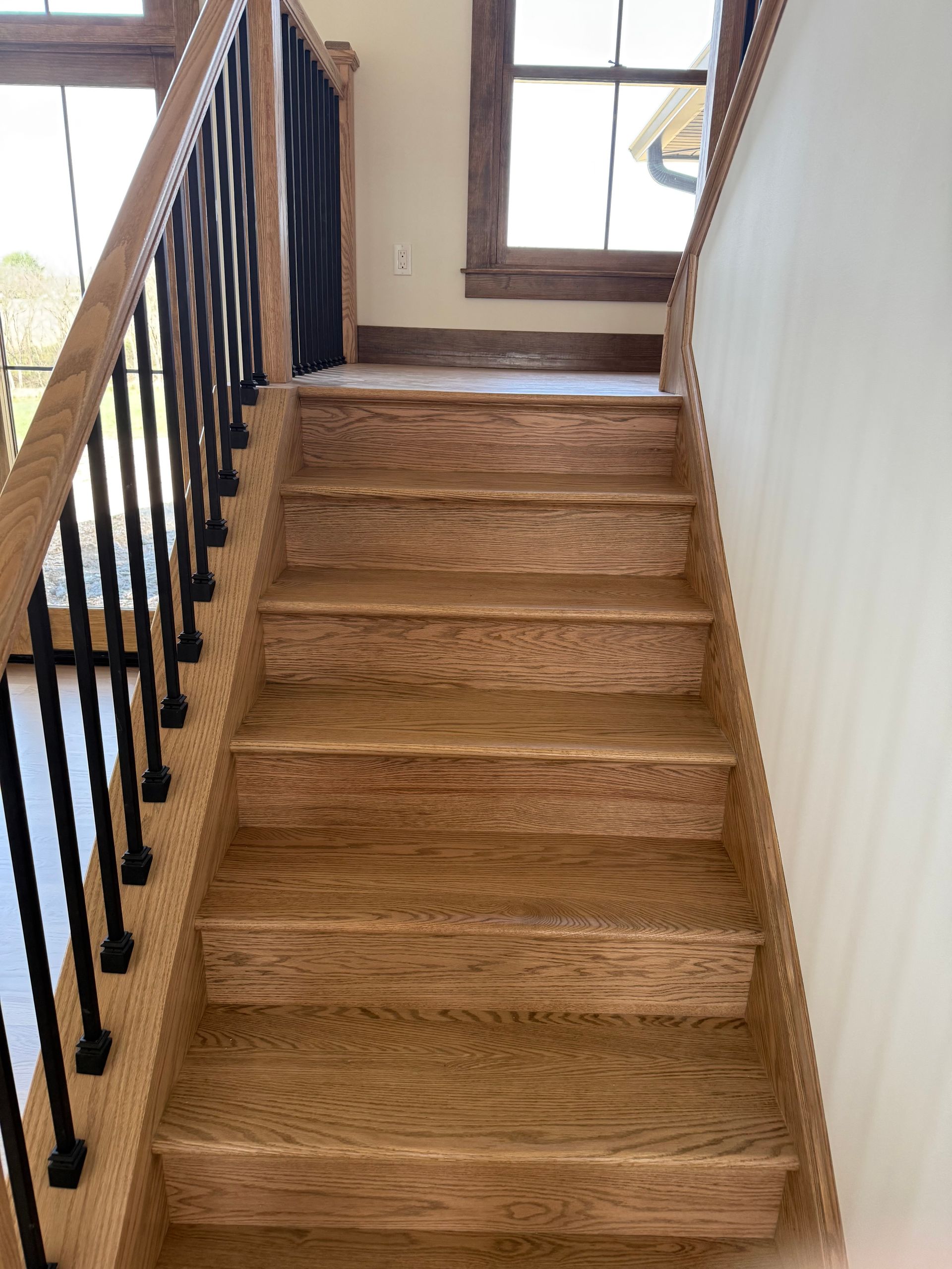 A wooden staircase with a black railing and a window.