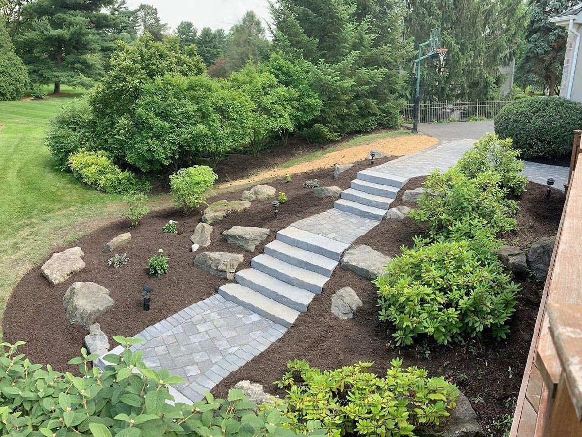 A stone walkway with stairs leading up to a house surrounded by trees and bushes