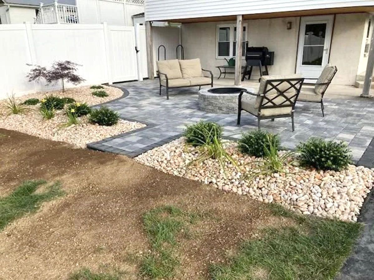 A patio with a fire pit and chairs in the backyard of a house