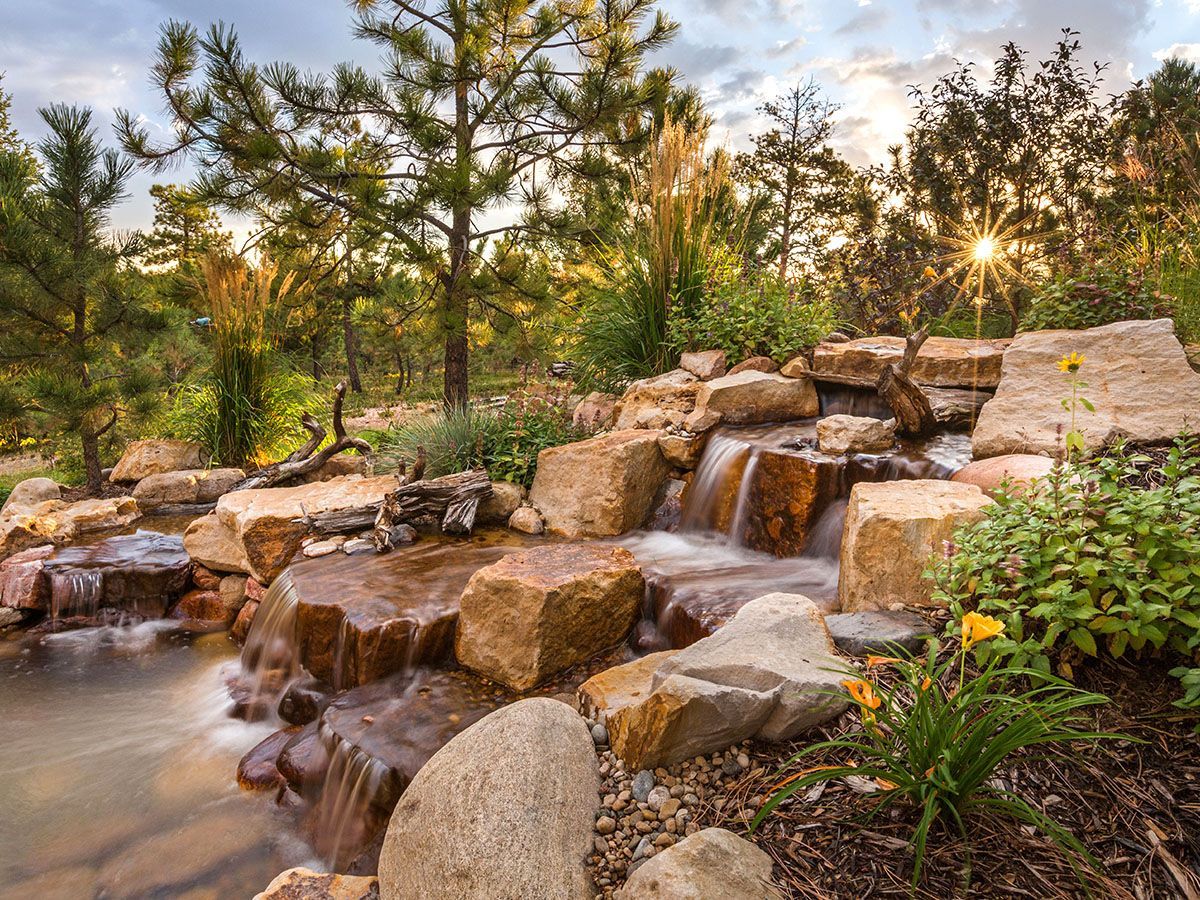 A waterfall is surrounded by rocks and trees