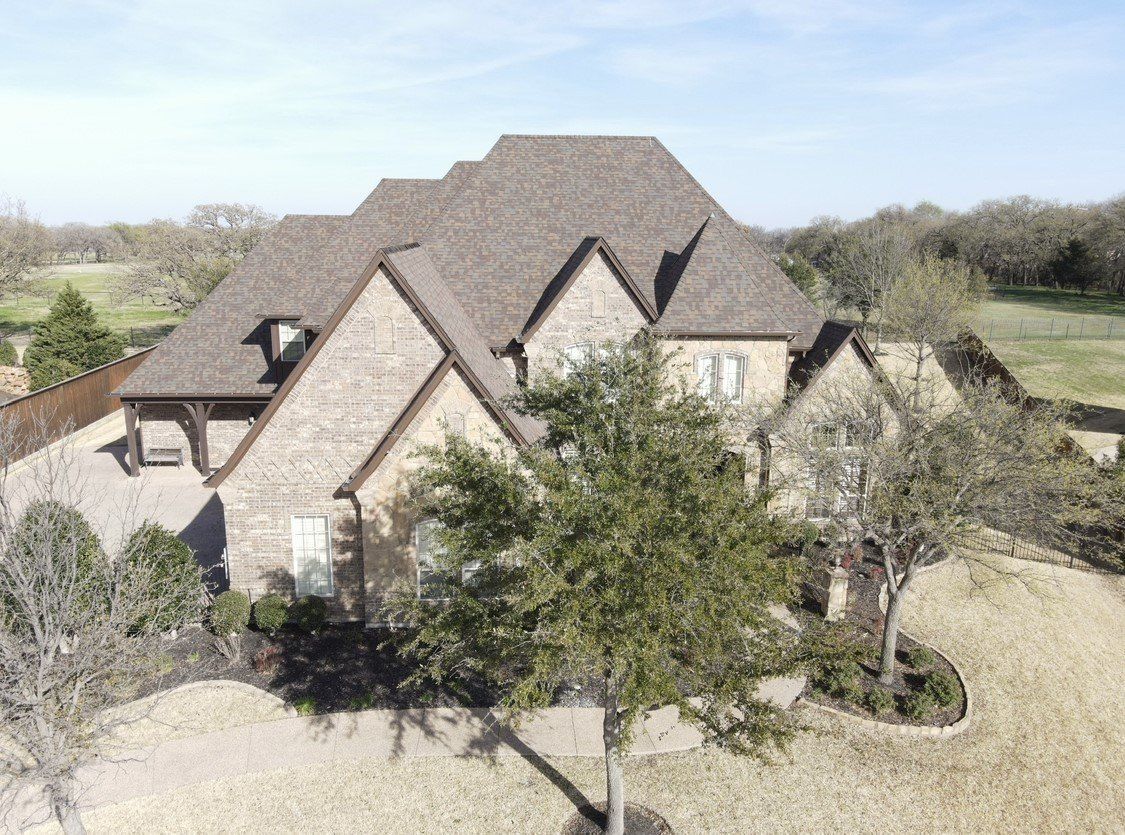 An aerial view of a large brick house with a tree in front of it.