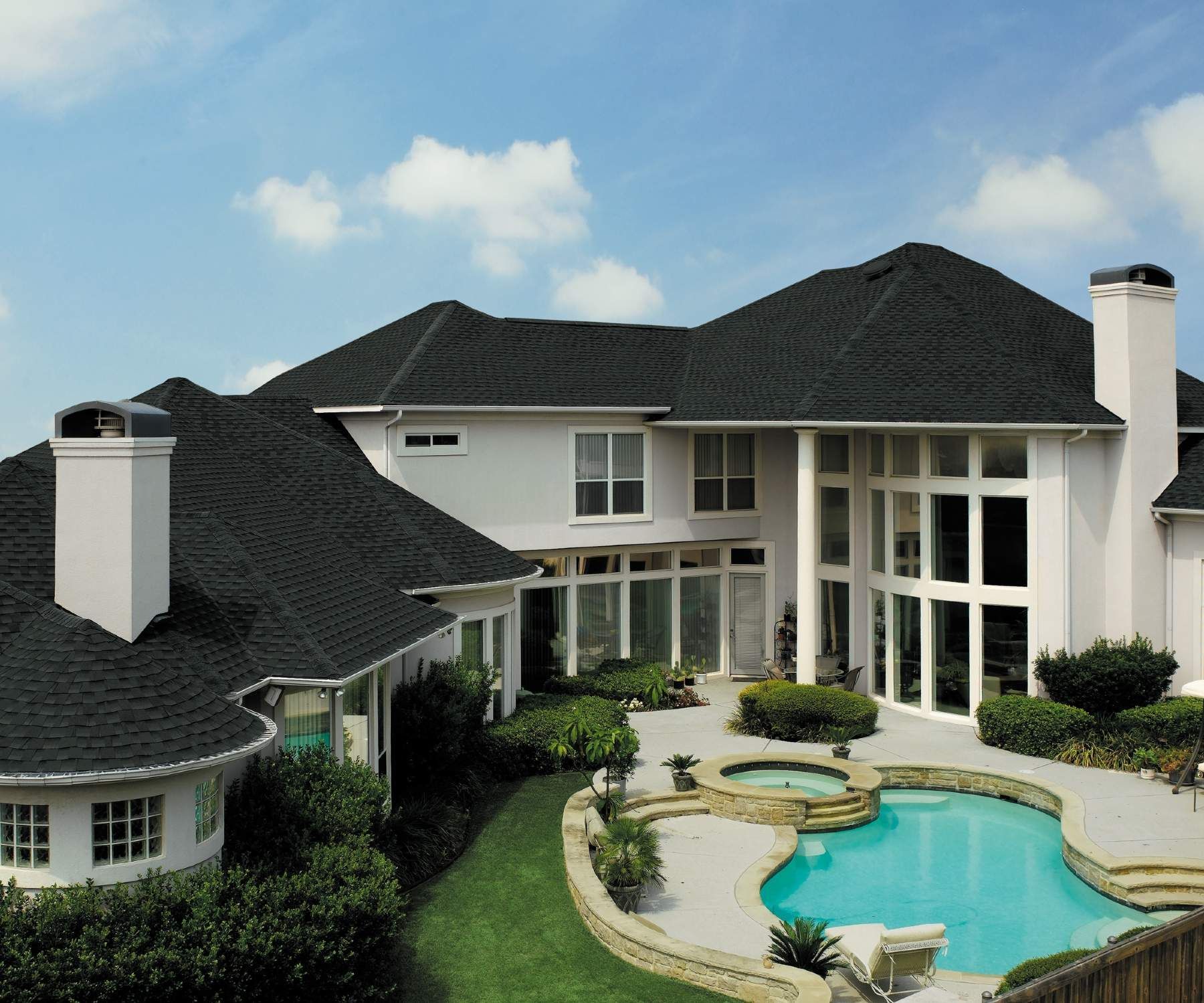 A large white house with a black roof and a swimming pool