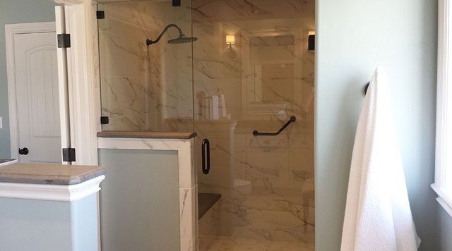 Bathroom with walk-in tiled shower, glass door, and towel hanging by a bright window.