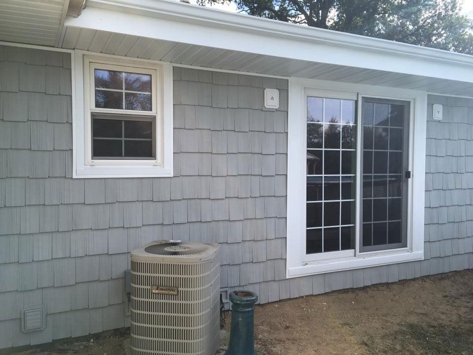 Gray house exterior with a window, sliding glass door, and AC unit.