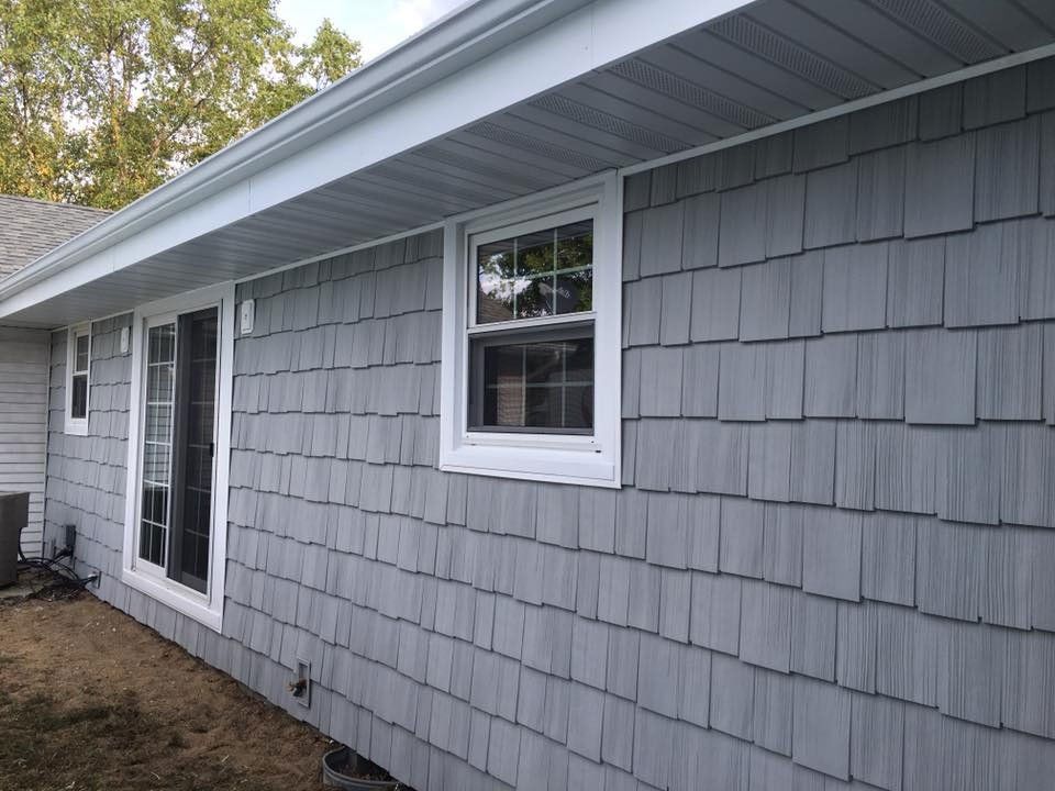 Gray shingle siding on a house with white trim around windows and doors.