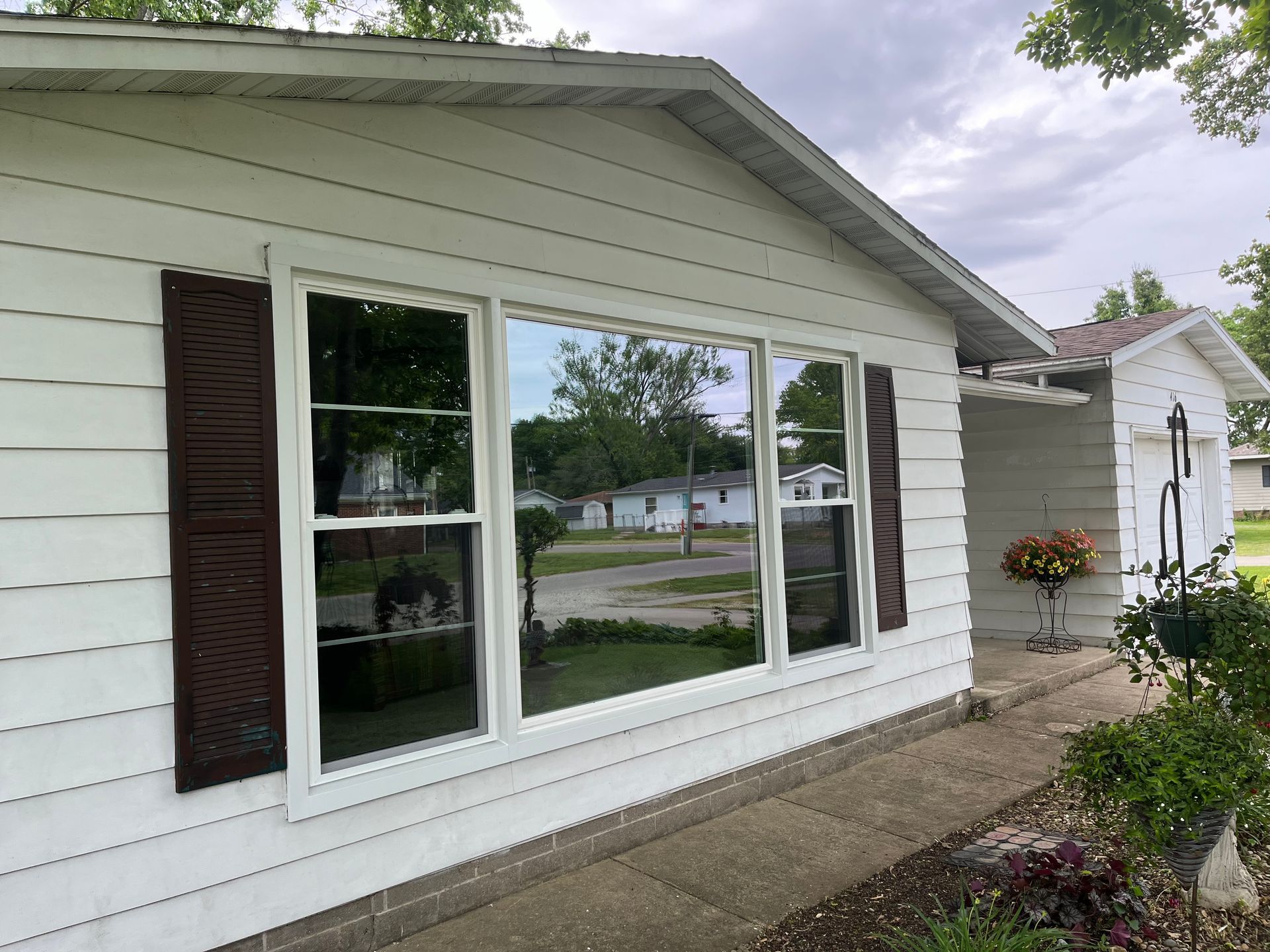 White house with brown shutters and reflective windows.