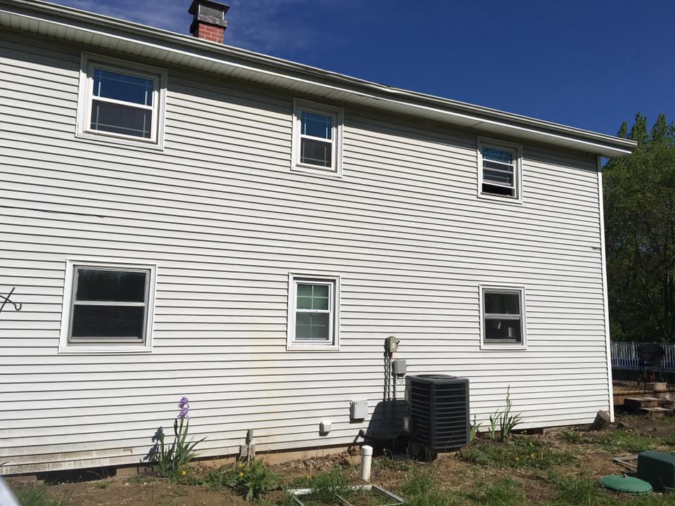 Two-story house with white siding, multiple windows, and air conditioning unit.