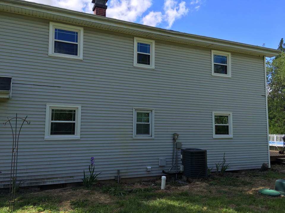 Two-story house with gray siding, six windows, and an air conditioning unit.