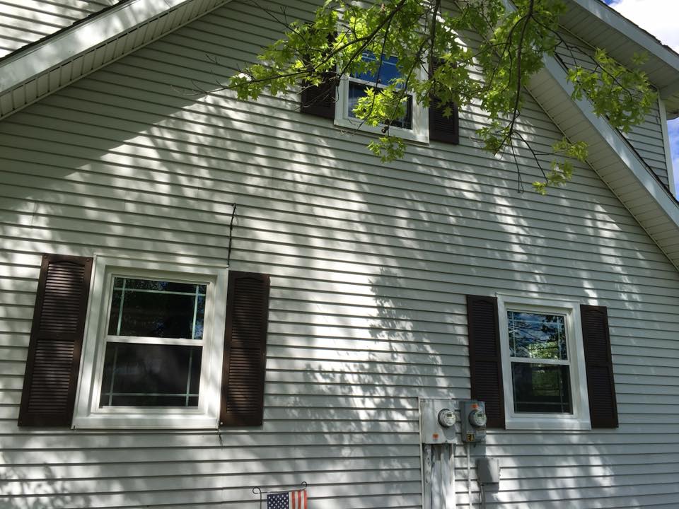 White house with brown shutters and windows, sunny day.