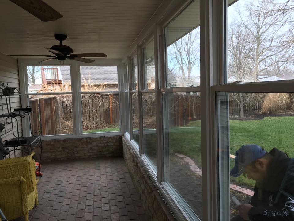 Sunroom with large windows overlooking a backyard; a person looks out the window.