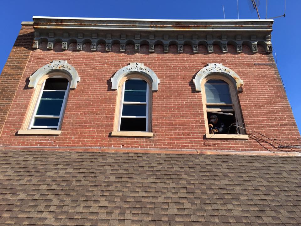 Red brick building with three arched windows, brown roof, and a blue sky.