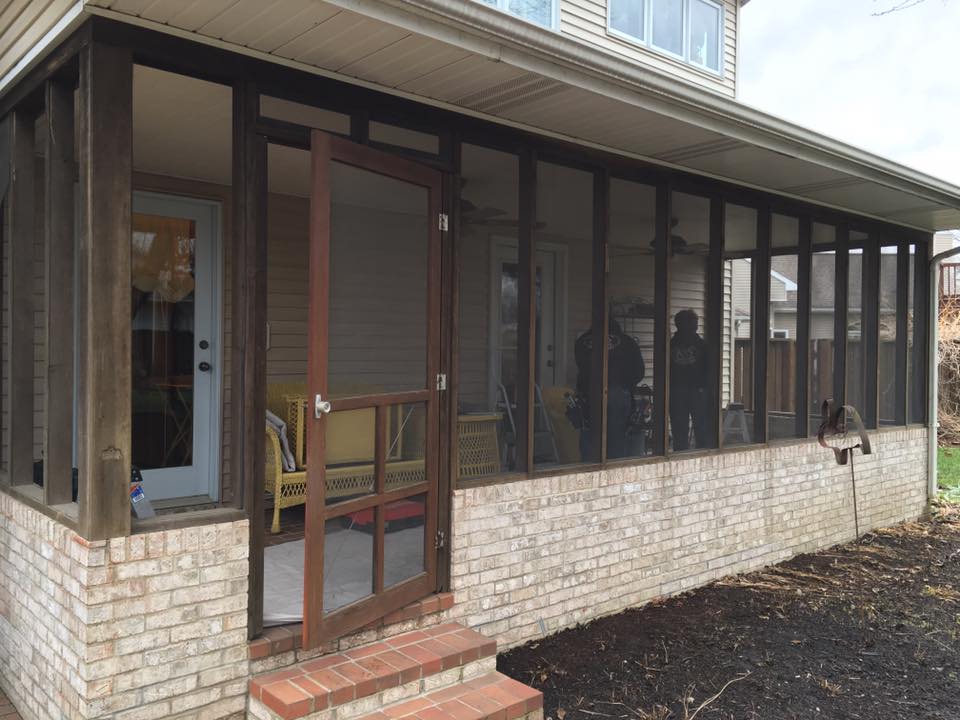 Screened porch with brick base, brown frames, and a door leading outside.