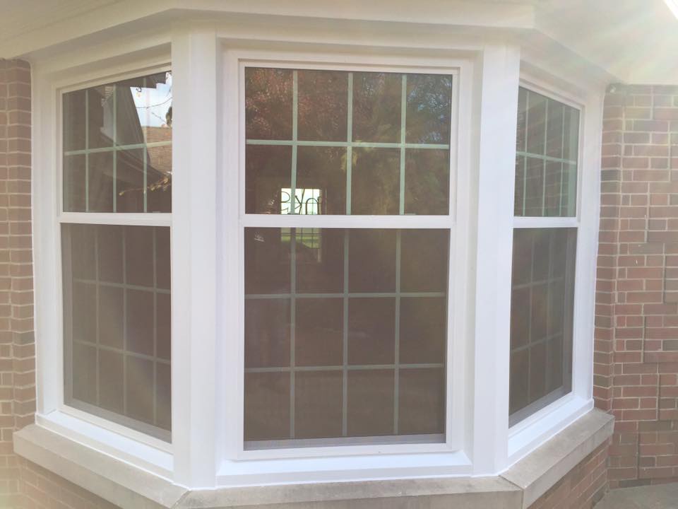 Bay window with white frames and grids, set in a brick wall.