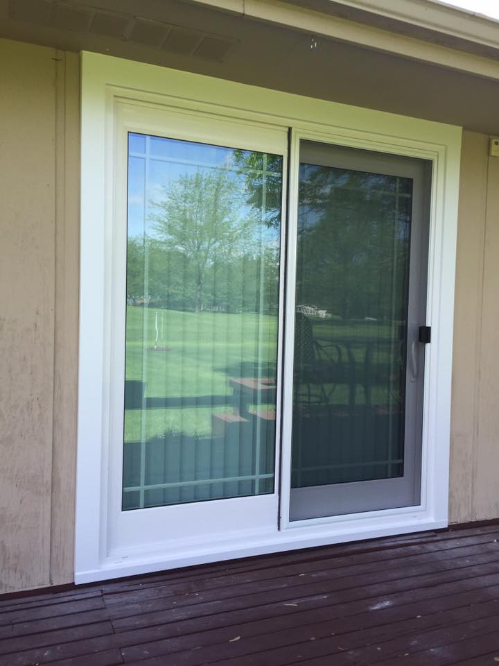 Sliding glass door with white trim on a brown deck, showing the outside yard.