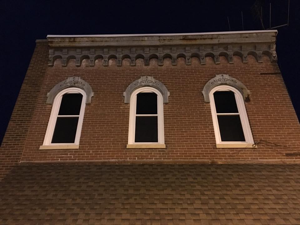 Brick building facade with three arched windows; night setting.