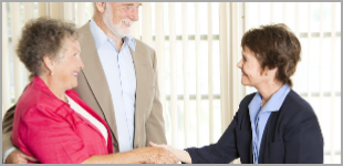 Happy elderly couple shaking hands with consultant in law firm