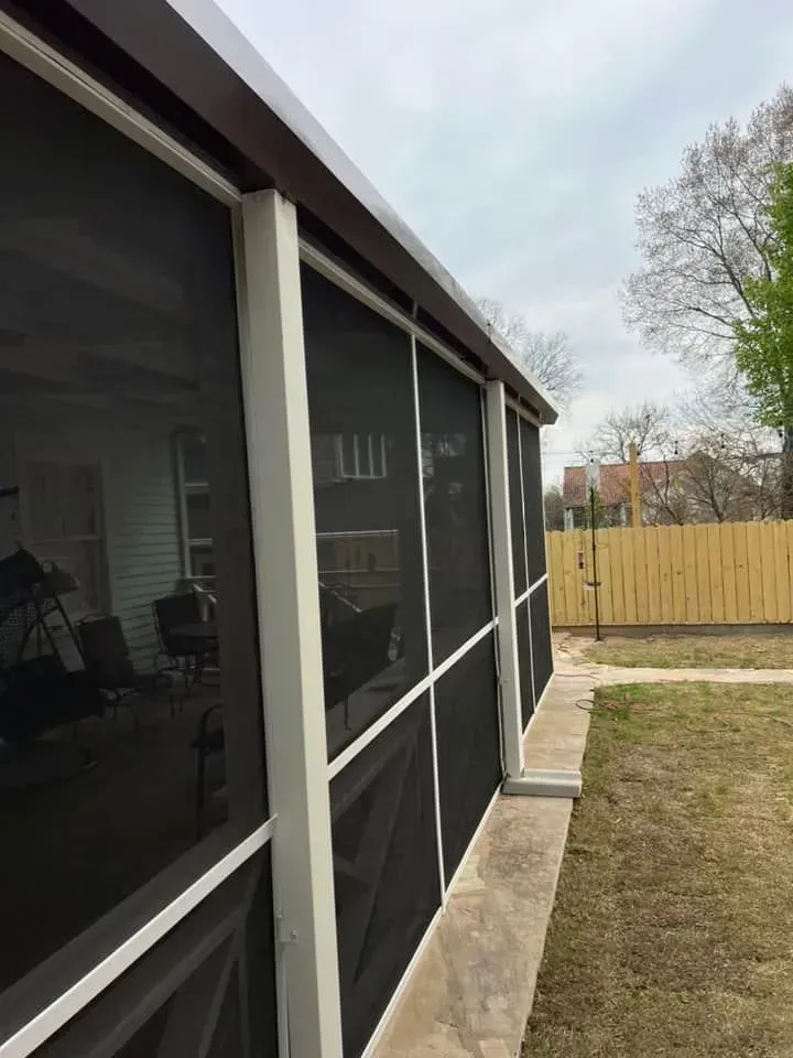A screened in porch with a wooden fence in the background