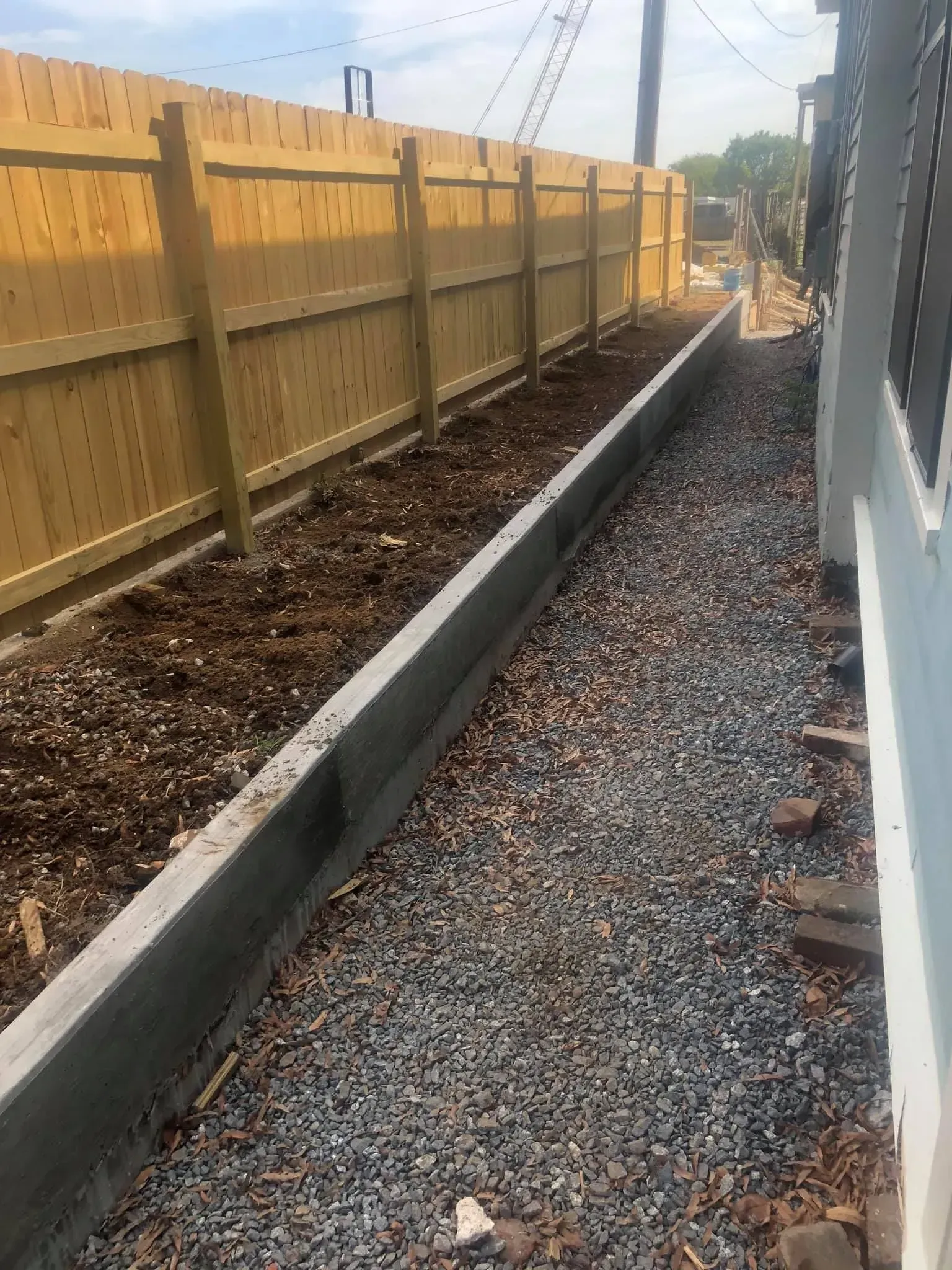 A wooden fence is being built next to a gravel path.