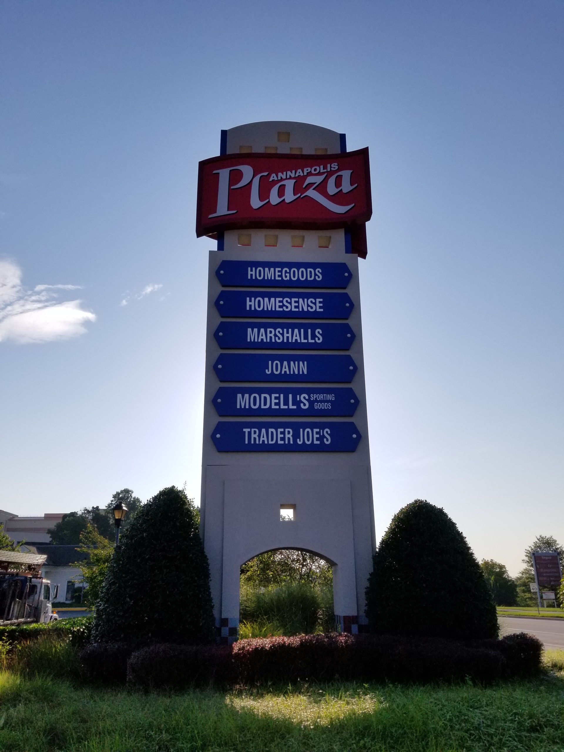 A large sign that says plaza is in the middle of a grassy field.