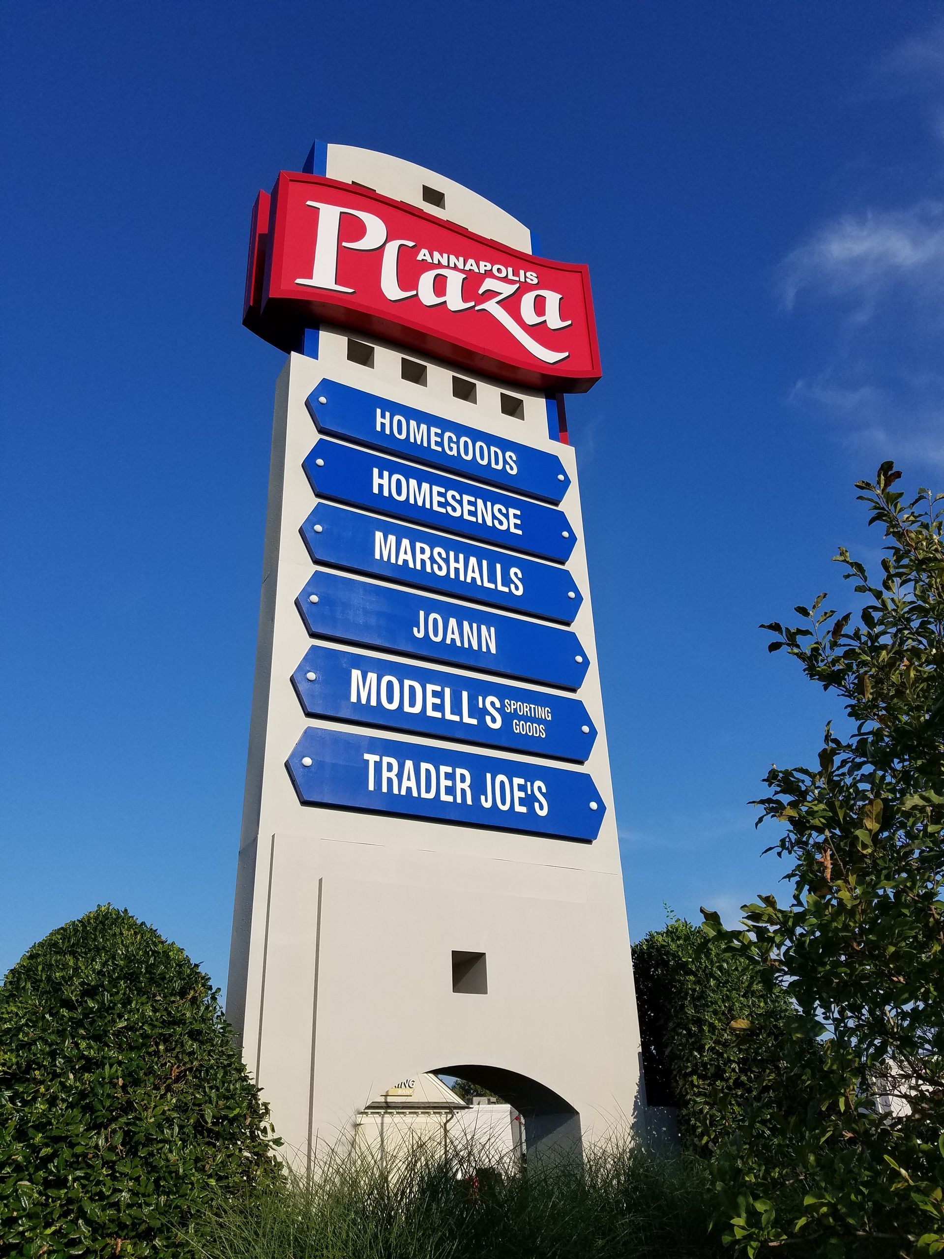A sign for the plaza has a lot of blue signs on it