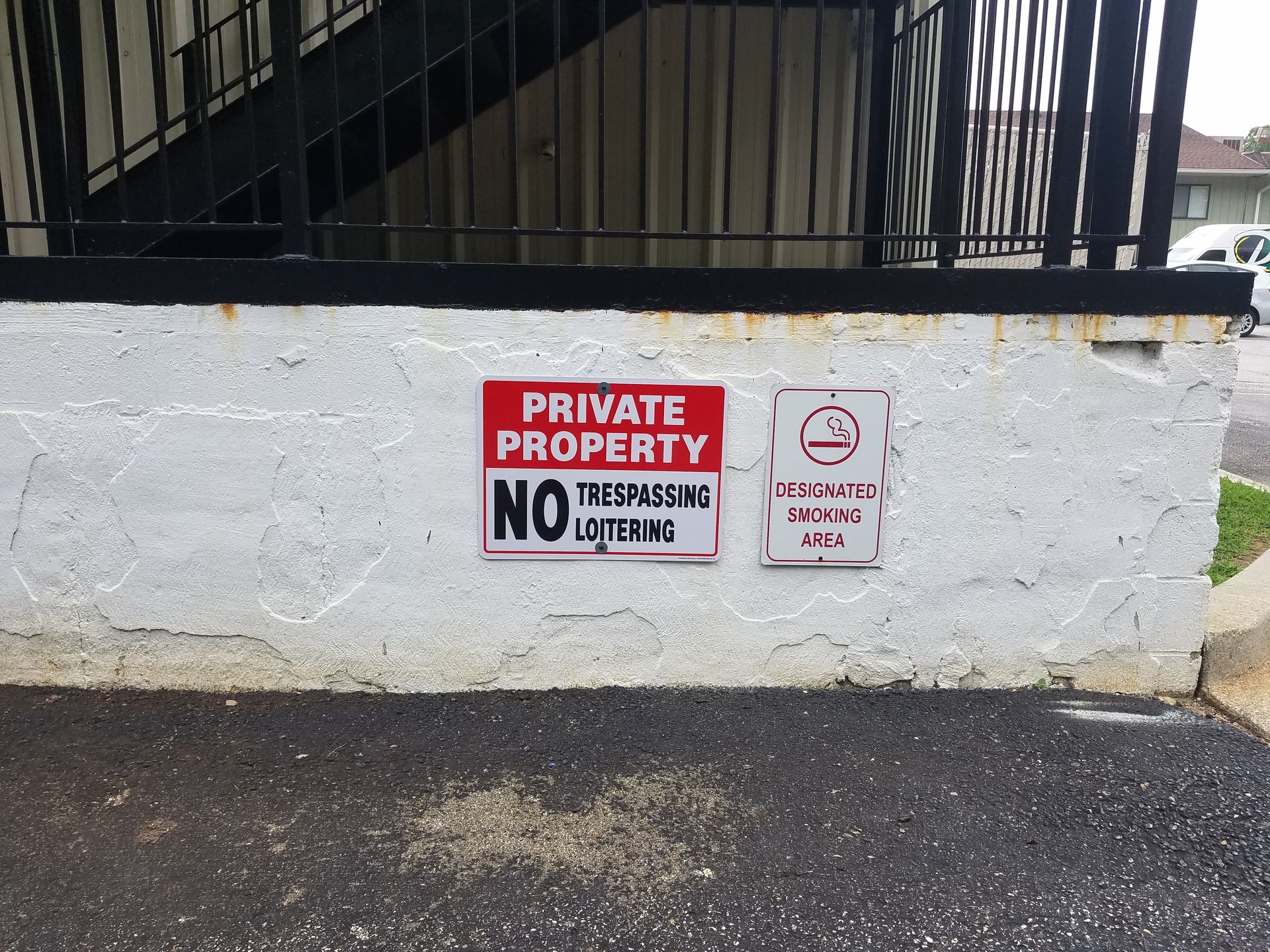 A white wall with a red sign that says private property