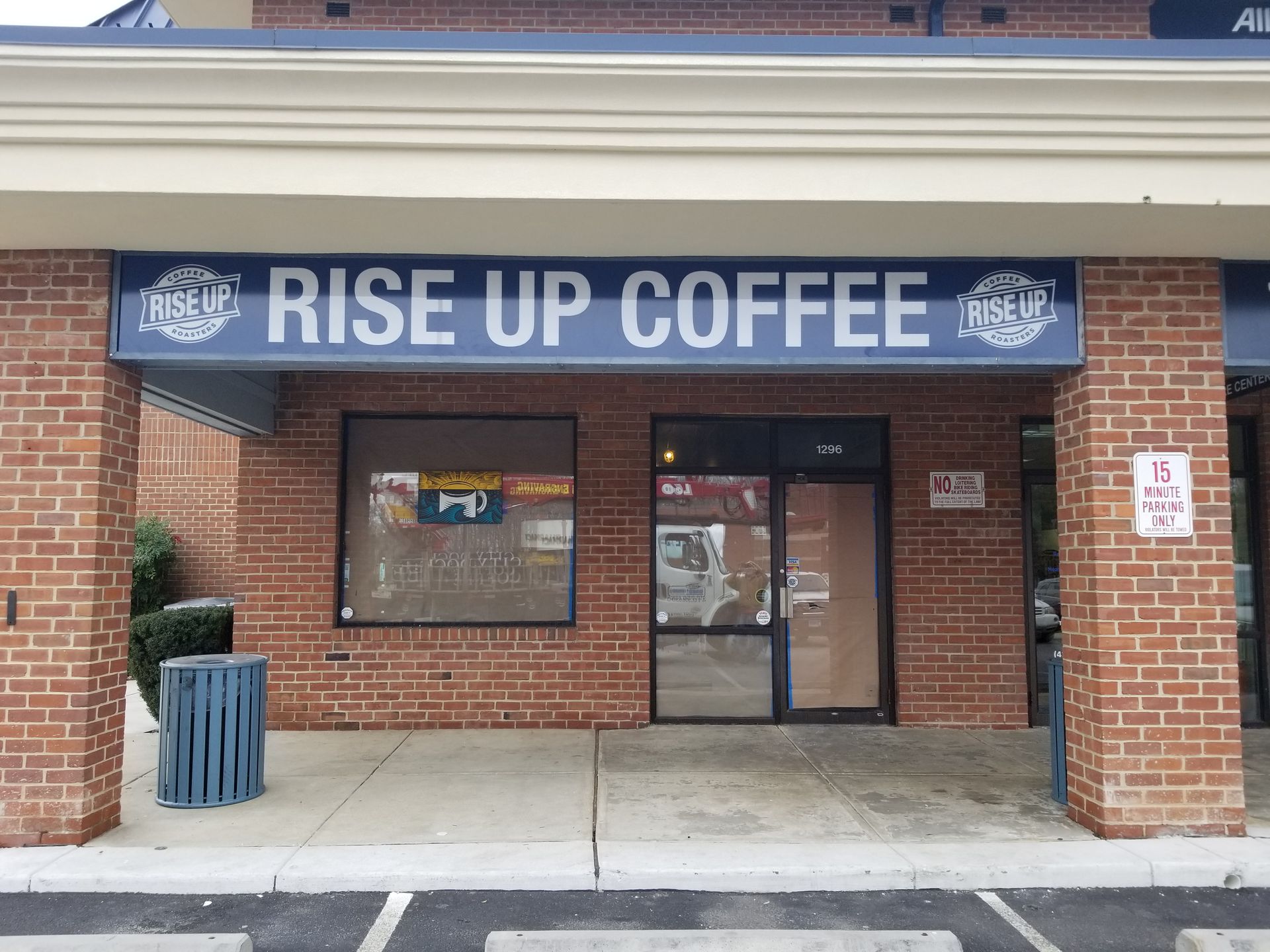 A brick building with a sign that says rise up coffee