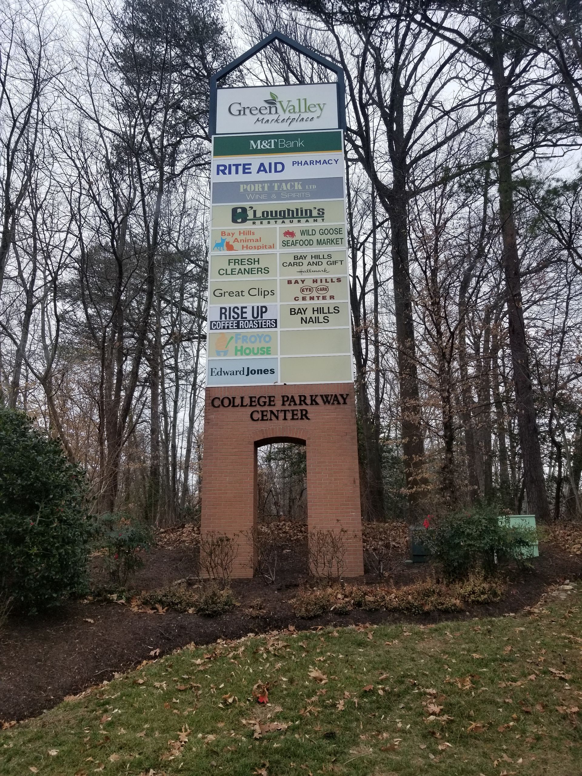 A large sign in the middle of a park with trees in the background.