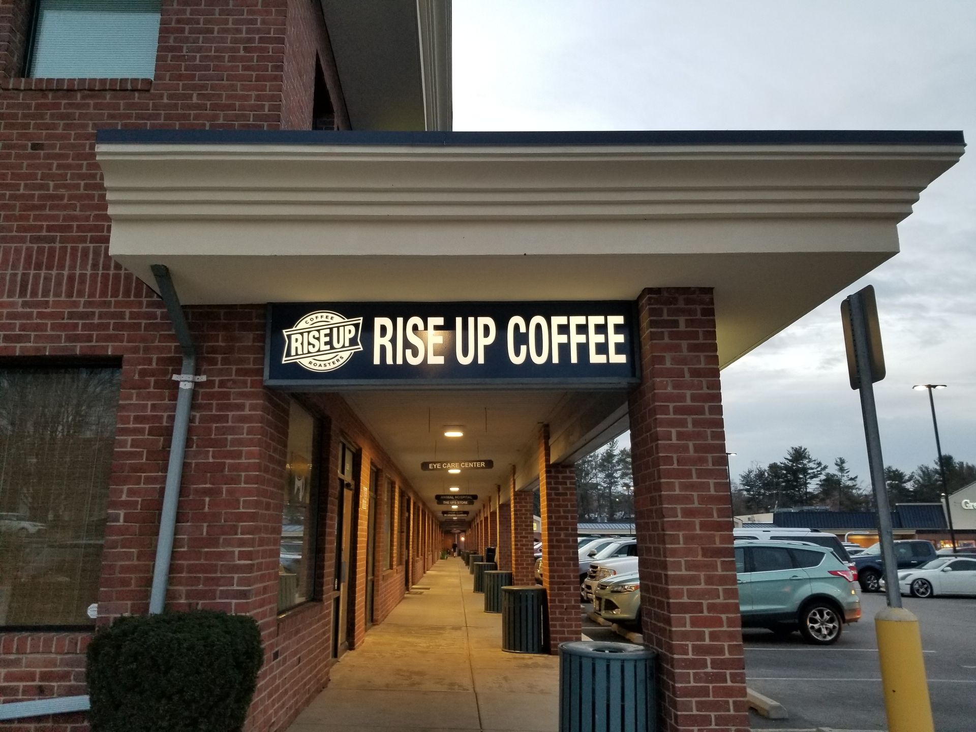 A brick building with a sign that says rise up coffee