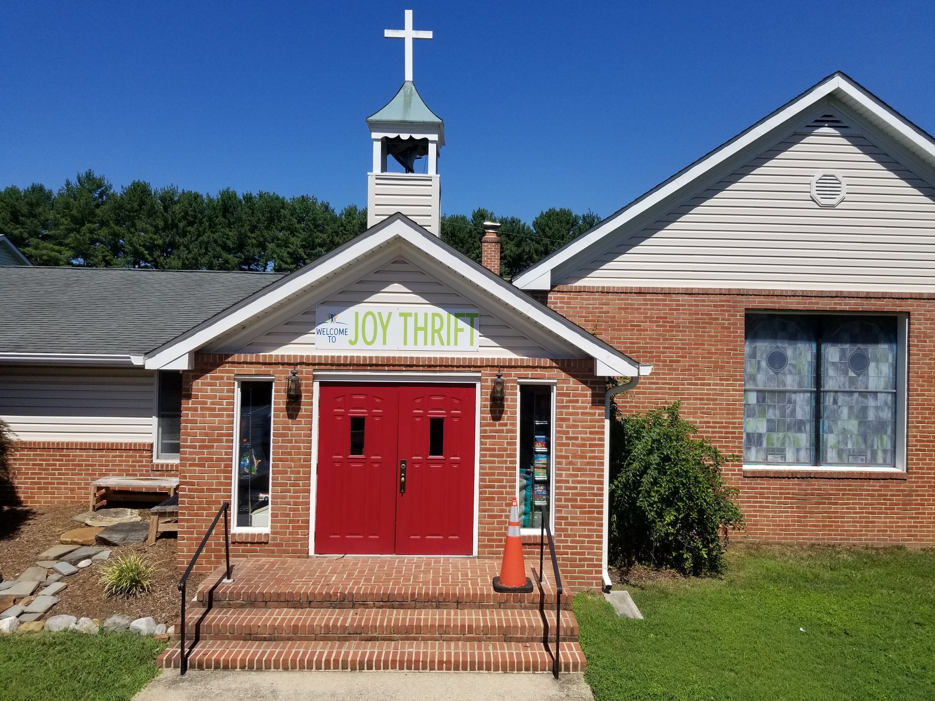 A church with a red door and a cross on top of it.