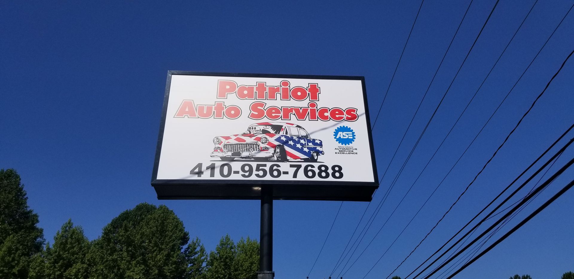 A sign for patriot auto services is hanging from a pole