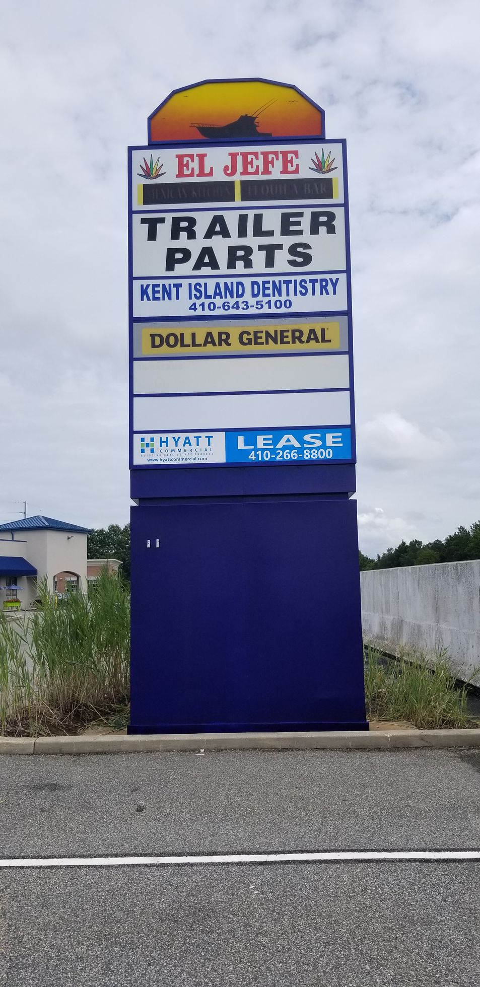 A blue sign for trailer parts is sitting on the side of the road.