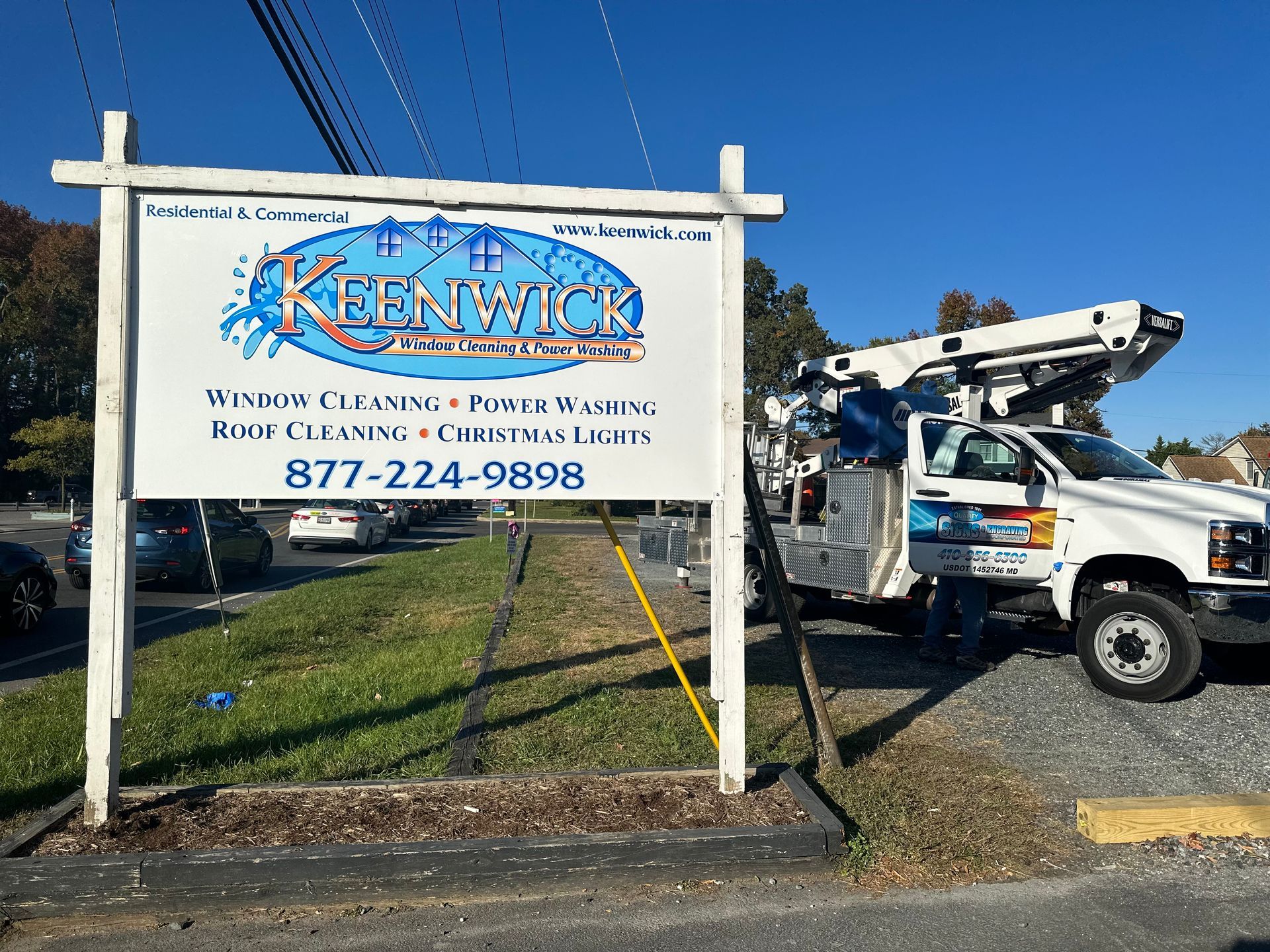 A white truck is parked in front of a sign for keenwick