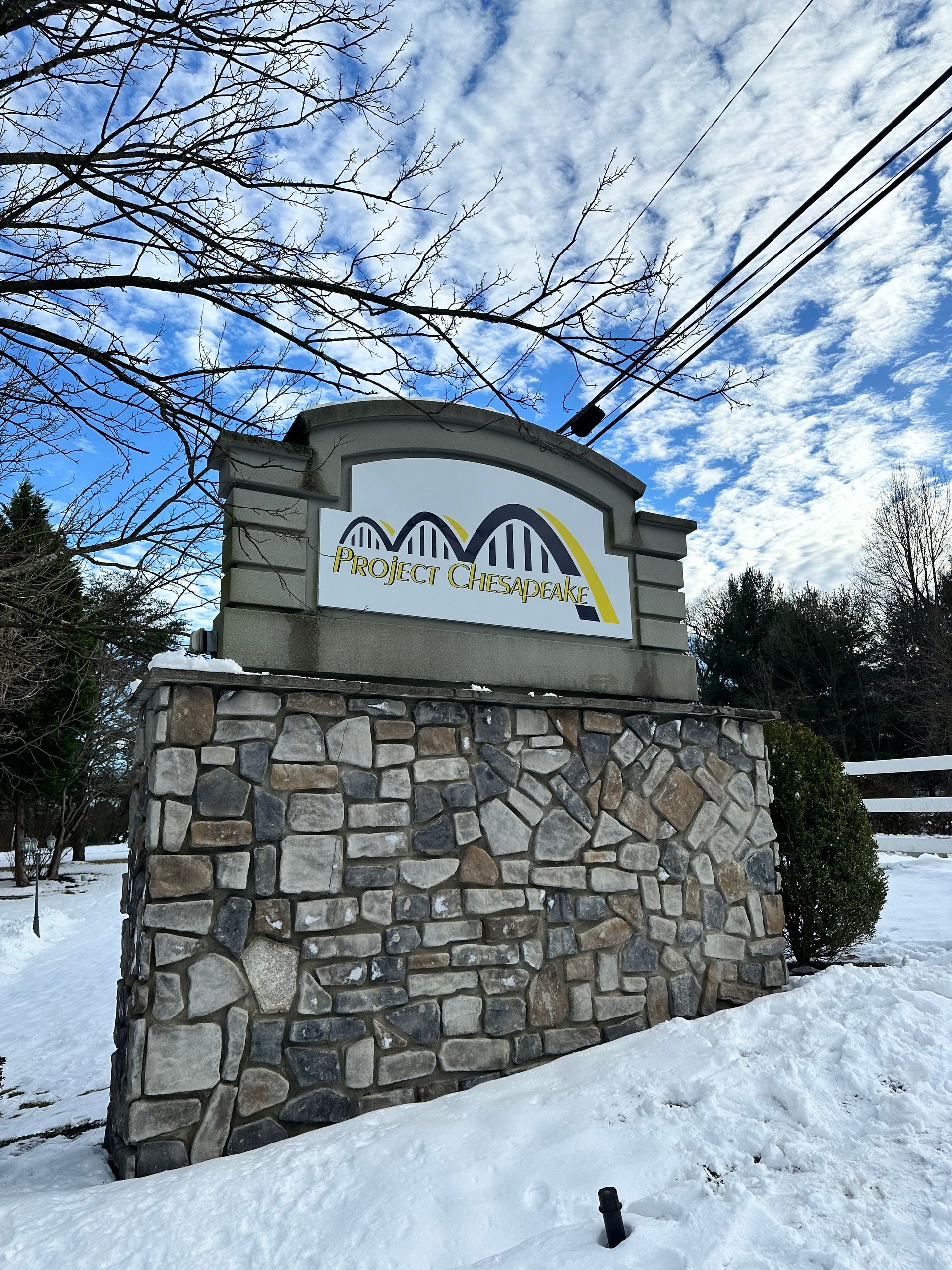 A stone wall with a sign on it in the snow.