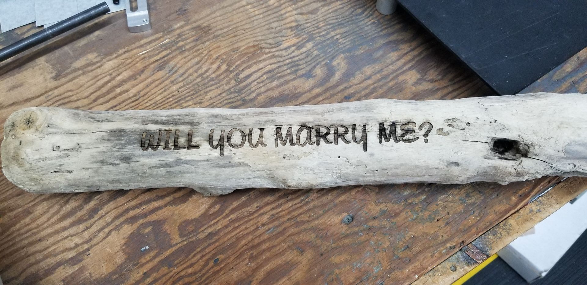 A piece of driftwood with the words `` will you marry me '' written on it