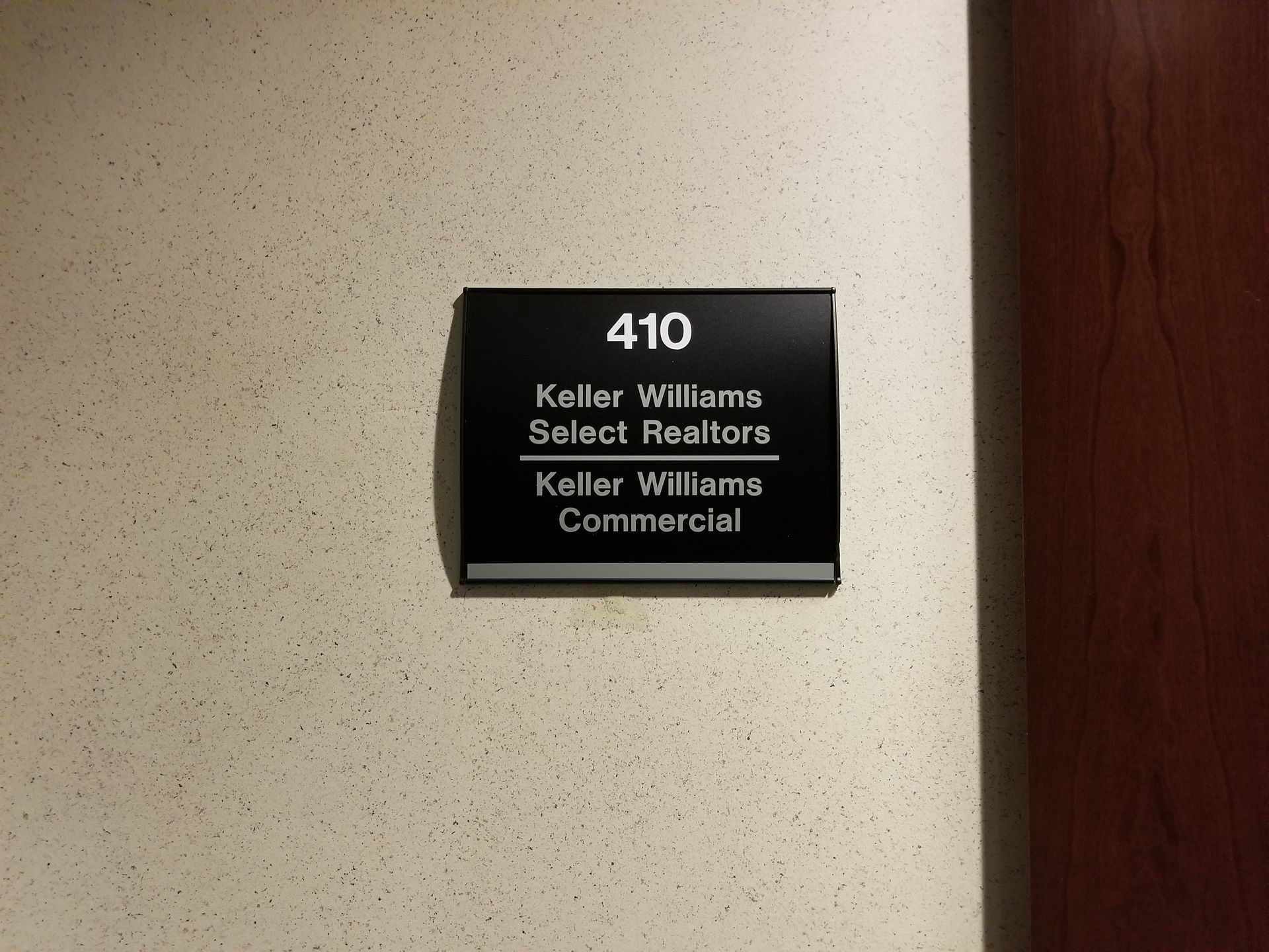 A sign for keller williams select realtors hangs on a wall