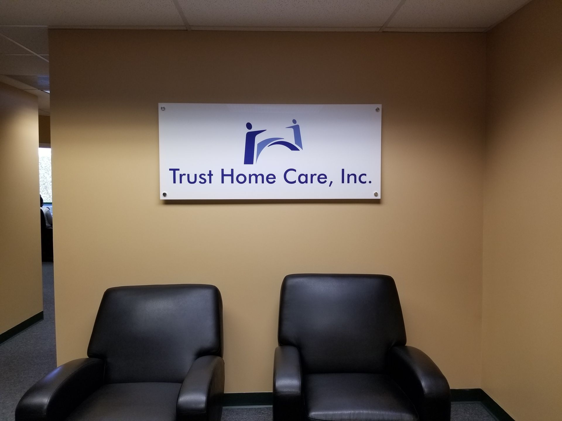 Two chairs in front of a sign that says trust home care inc.