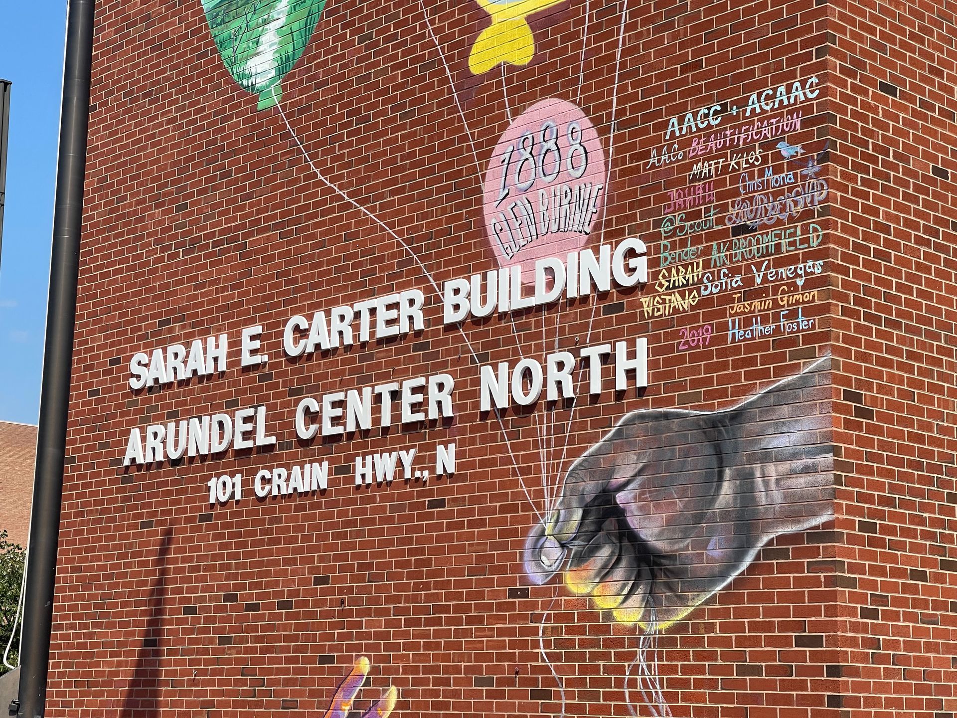 A mural on the side of a brick building says sarah e carter building arundel center north