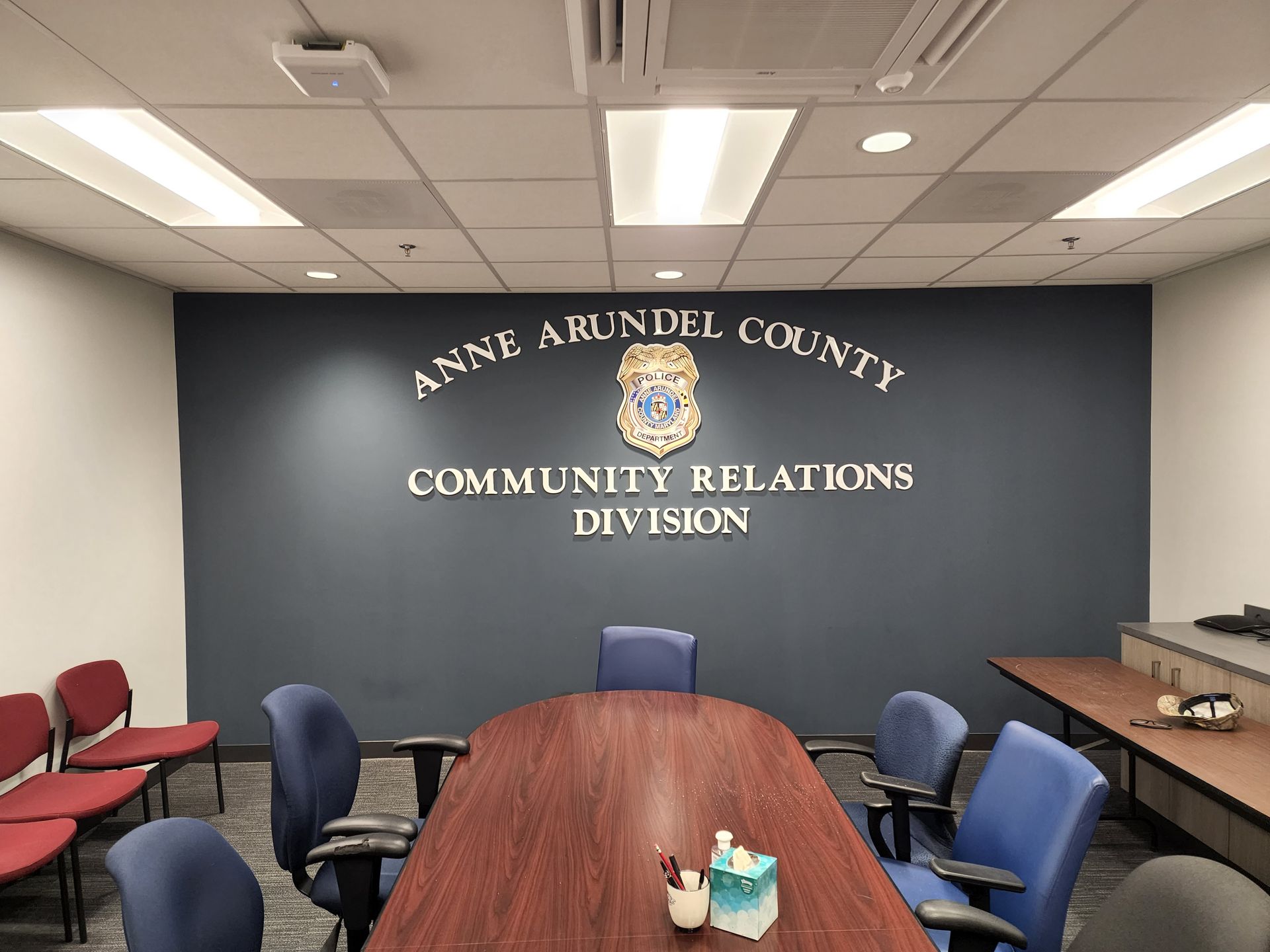 A conference room with a table and chairs and a wall that says anne arundel county community relations division