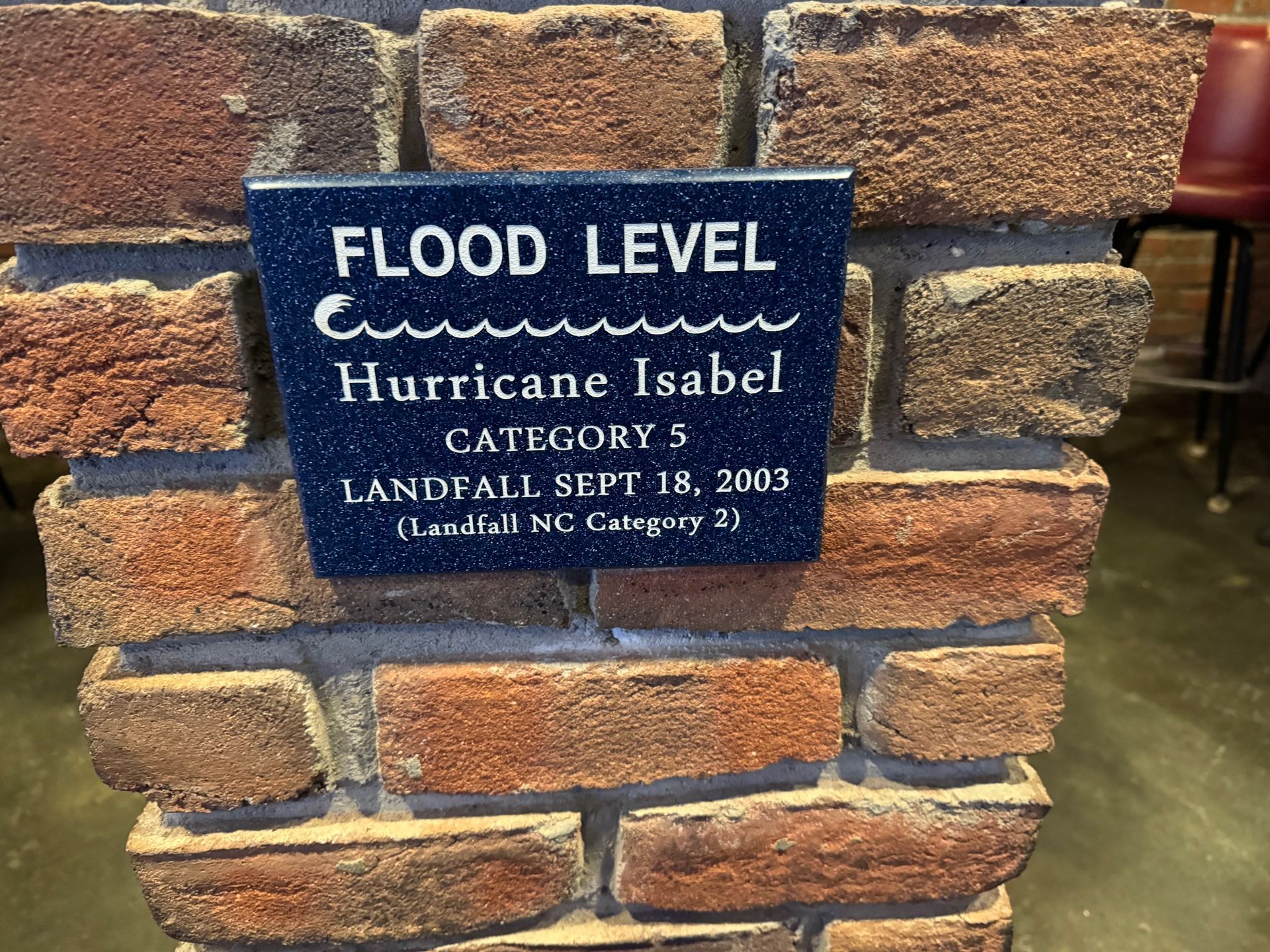 A sign on a brick wall says flood level hurricane isabel